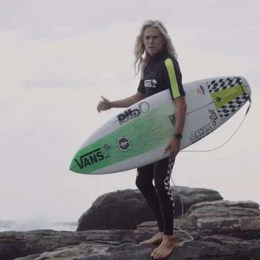 a woman holding a surfboard on top of a rocky beach