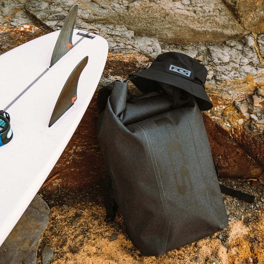 a surfboard and a bag sitting on a rock